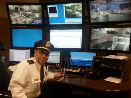 Decorative image. Smithsonian Office of Protection Services Security Guard seated at a surveillance system desk.