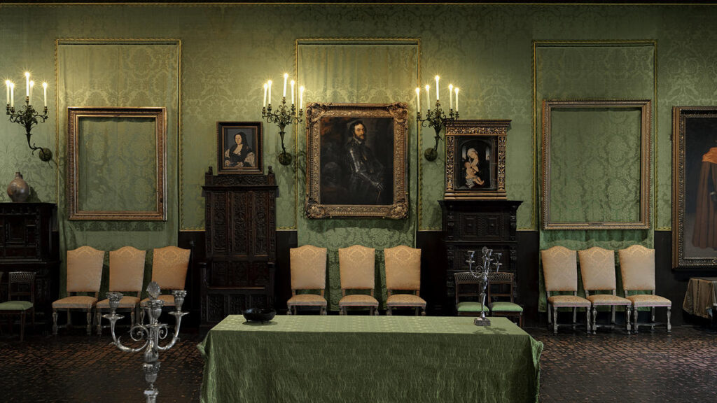 This photograph from the Dutch Room in the Isabella Stewart Gardner Museum depicts a wall in the gallery. There are four paintings in frames and two empty frames, which represent the two pieces that were stolen.