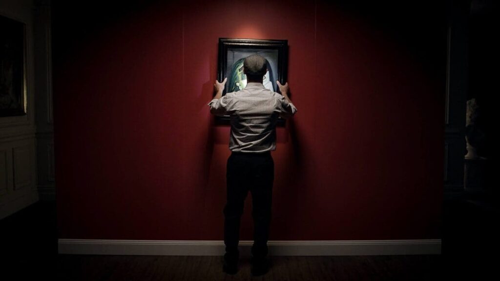 This ominous image depicts a man removing a framed painting from a wall. The students that proposed a theft will need to meticulously consider each step of their plan if they hope to get away with it.