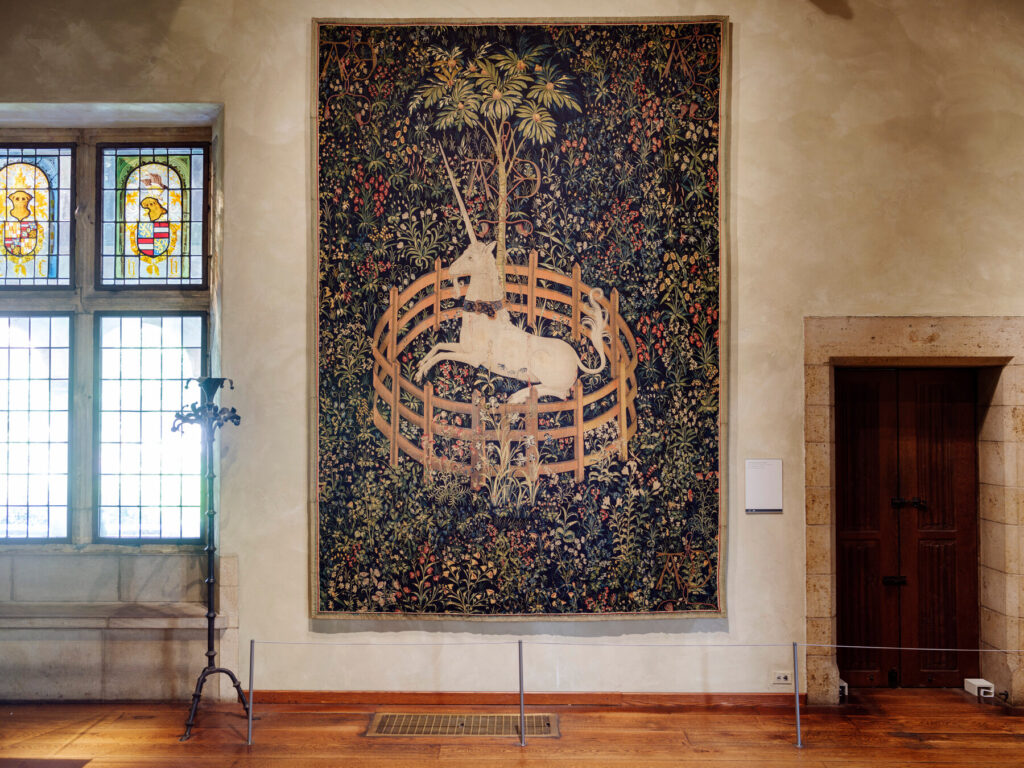 This image depicts the Unicorn Rests in a Garden tapestry where it is on display in the Metropolitan Museum of Art. It is included to provide the reader with visual perspective on how large the tapestry is.